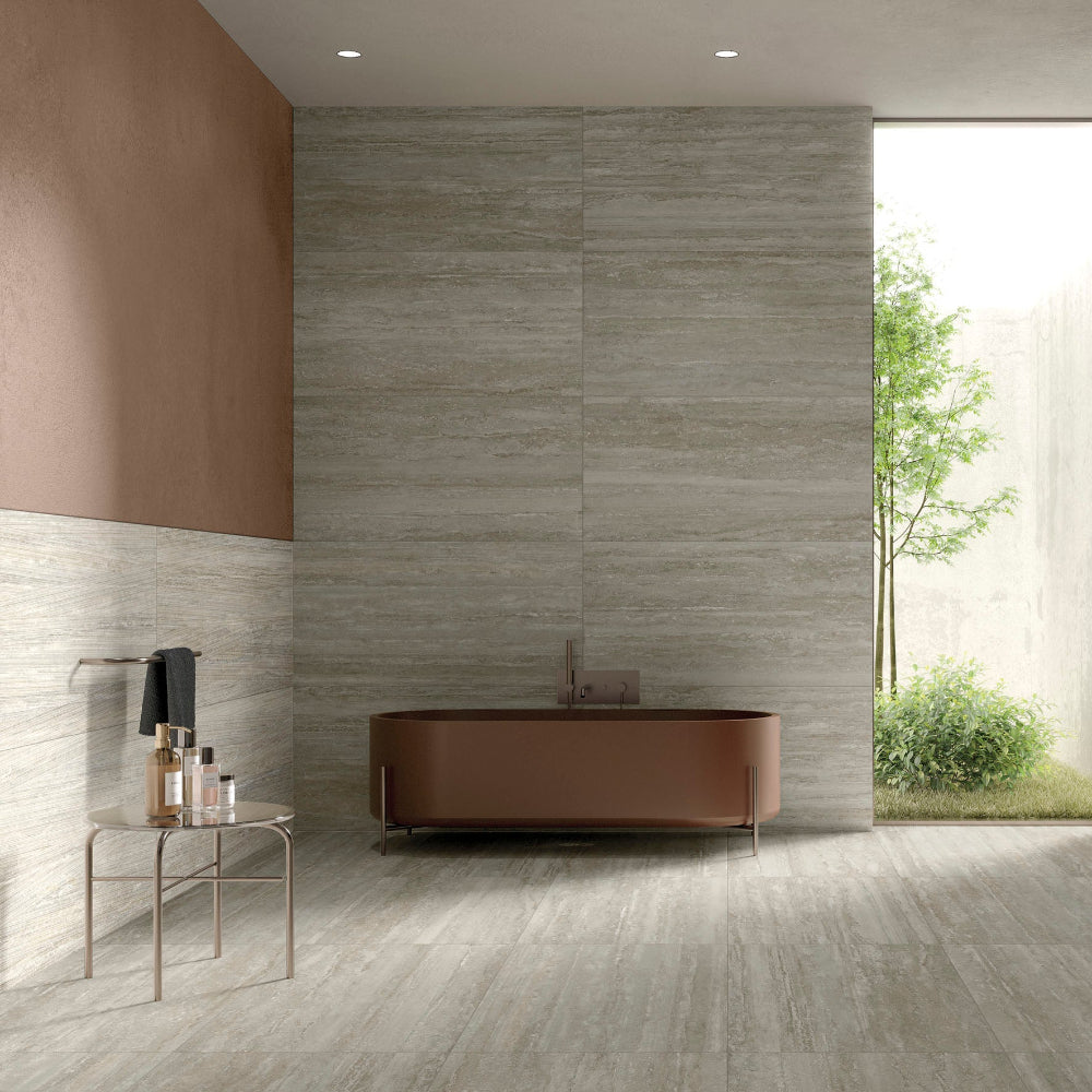 Modern bathroom with a bathtub, sink, and large window MGM Ceramiche travertino Grigio wall feature