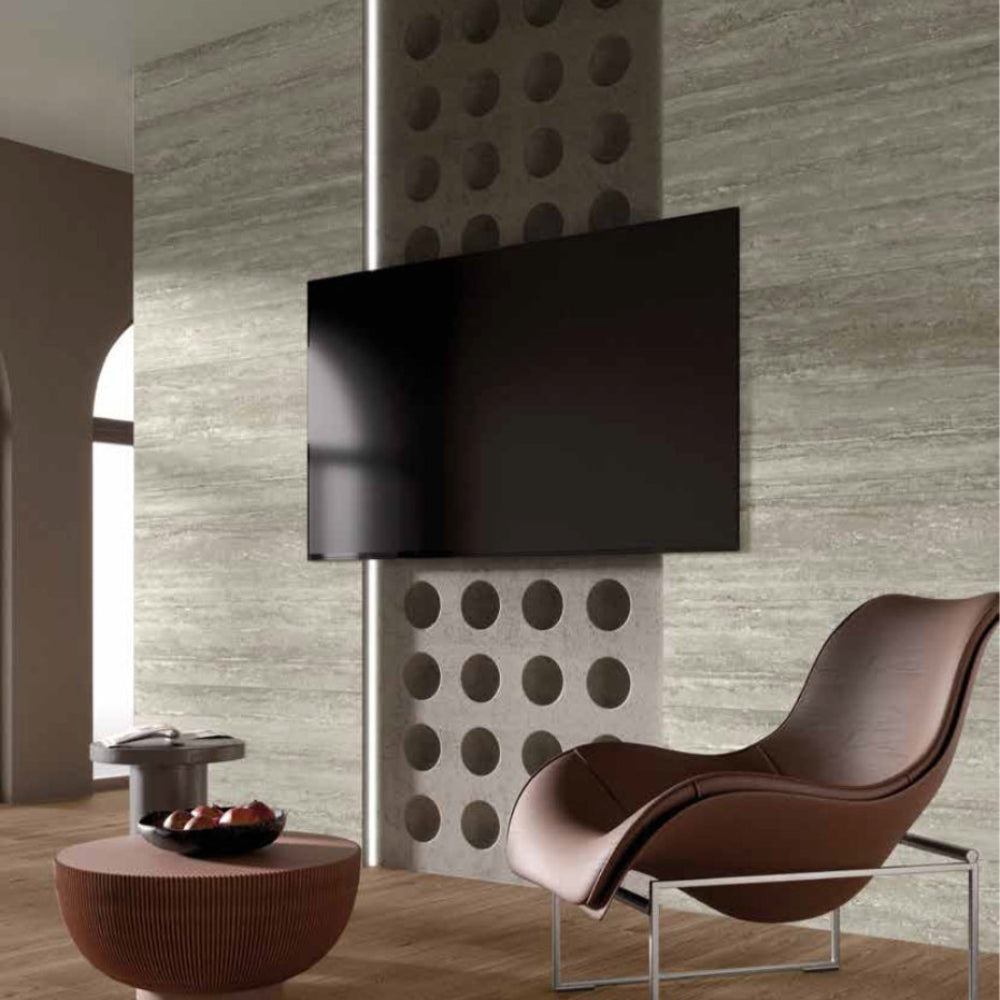 Modern interior design with a brown chair, round table, decorative wall panel with MGM Ceramiche Travertino Grigio tile wall backgroud 